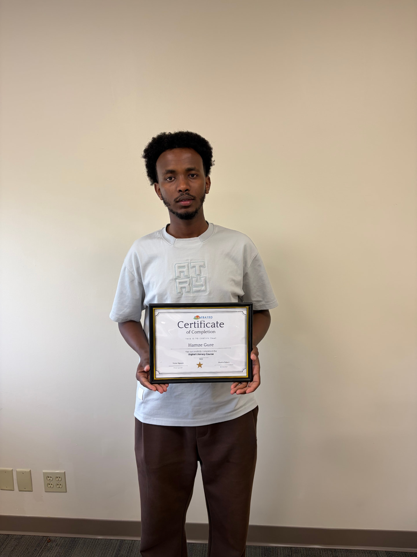 A Digital Literacy graduate proudly holding a framed certificate of completion