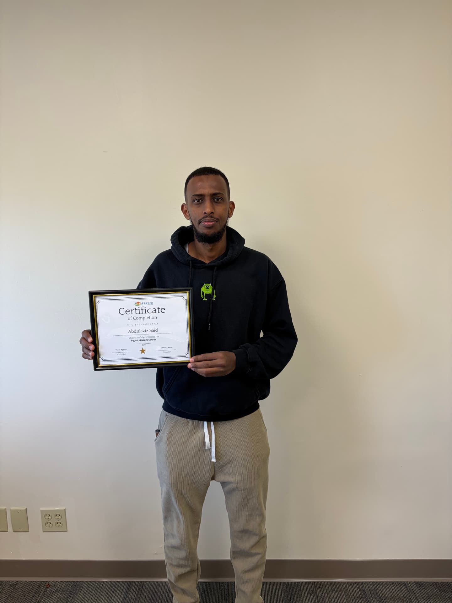A Digital Literacy graduate displaying a framed certificate of completion