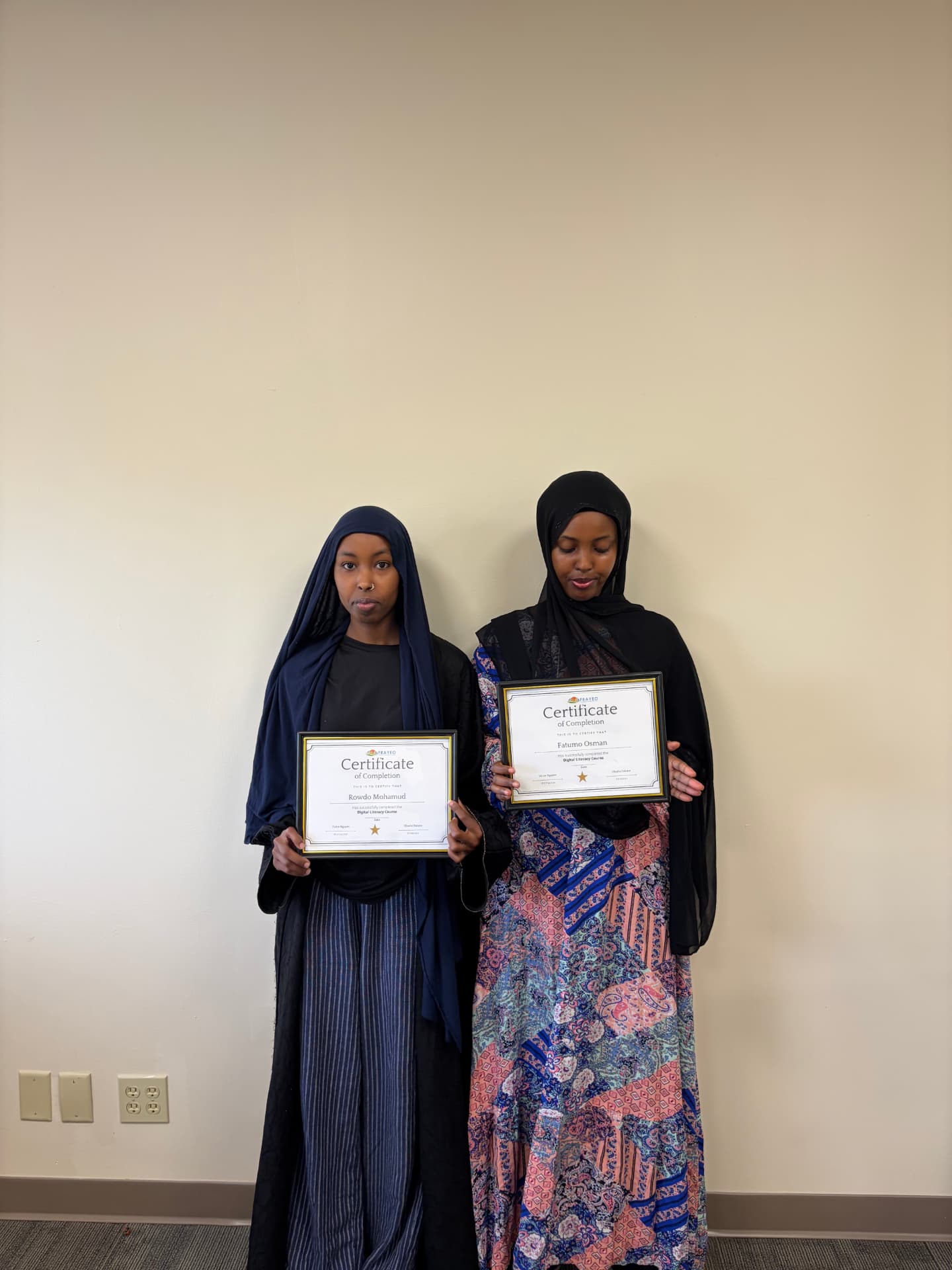 Two Digital Literacy graduates holding their framed certificates of completion